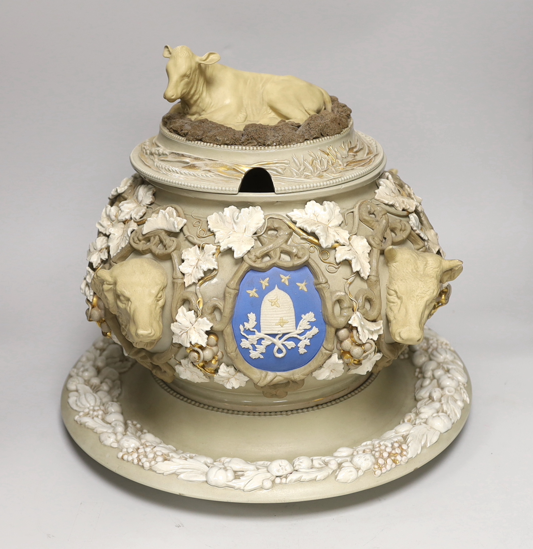 An impressive English cane ware and drab ware ‘agriculture’ soup tureen, cover and stand with cover, modelled with cattle, a dog and a horse’s head, amongst twining vines and crests, 38cm high